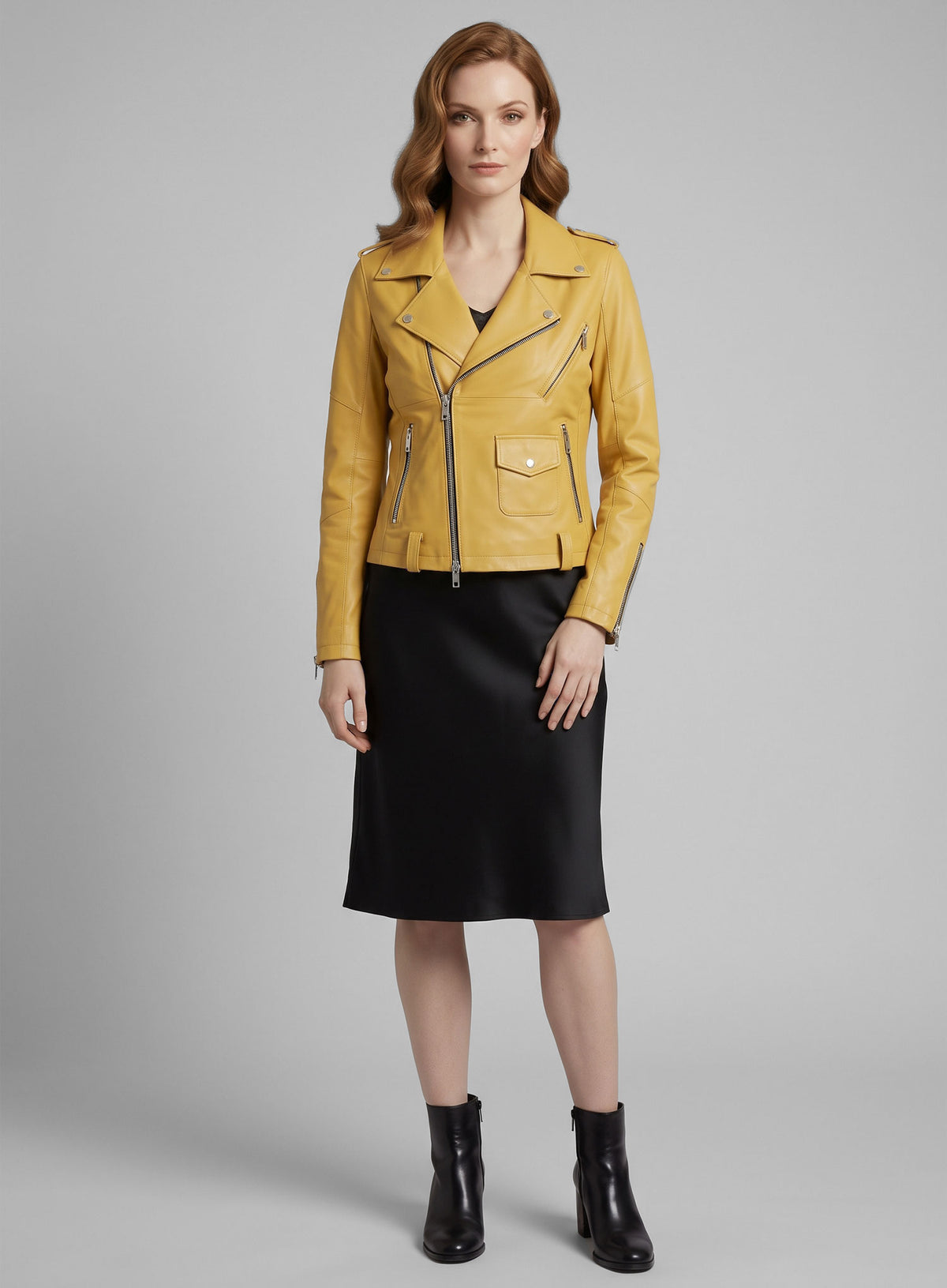 Full-length view of a woman in a yellow leather biker jacket, black satin skirt and black ankle boots