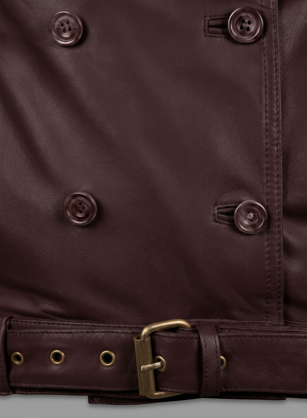Close-up of burgundy leather jacket buttons and belt with brass buckle and eyelets