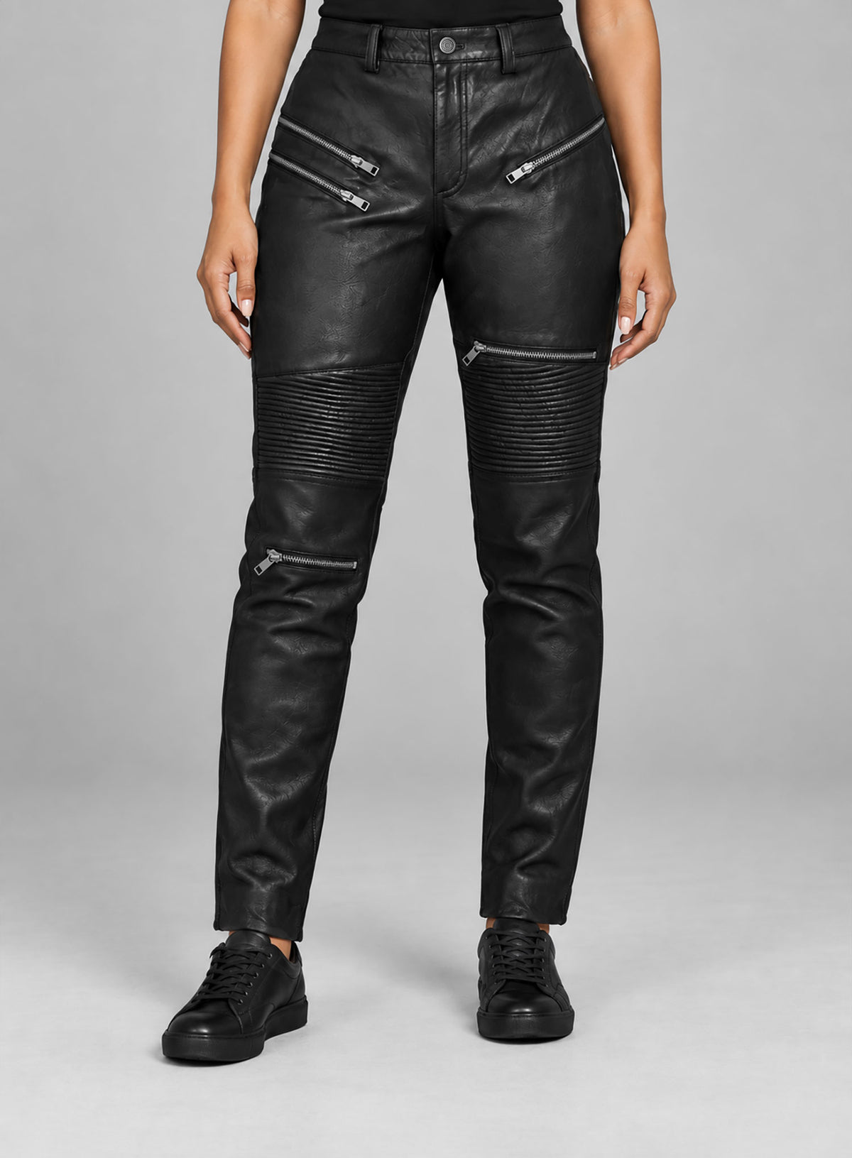 Woman wearing black leather biker pants with zip pockets and ribbed knee panels, front view