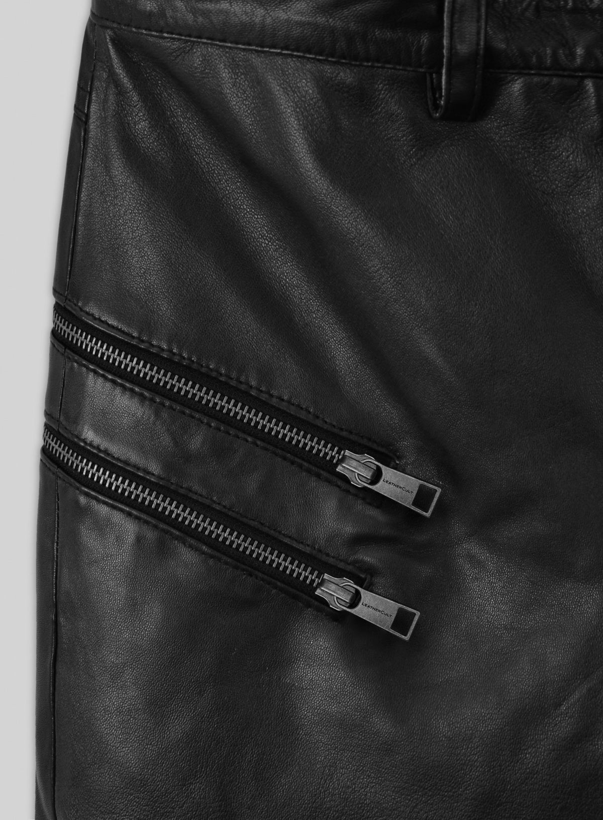 Close-up of two diagonal metal zippers on black leather pants