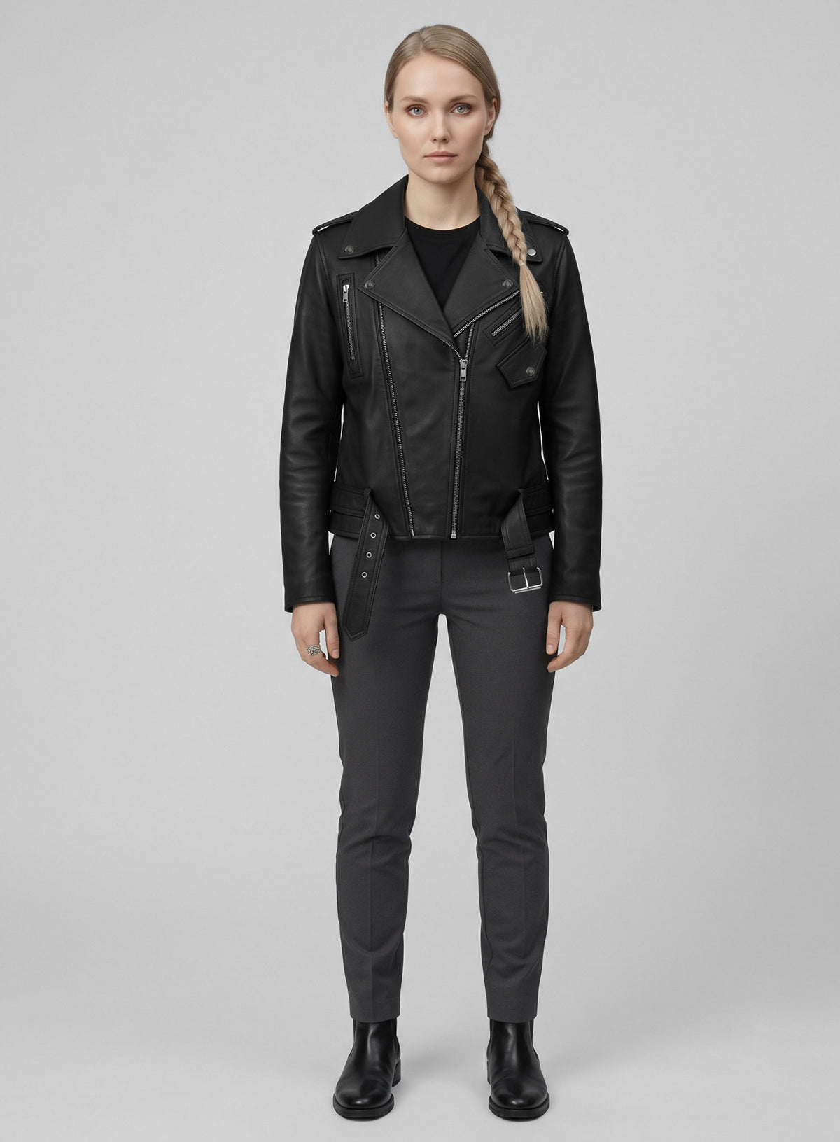 Full-length view of a woman in a black leather biker jacket with belt, grey trousers and black boots
