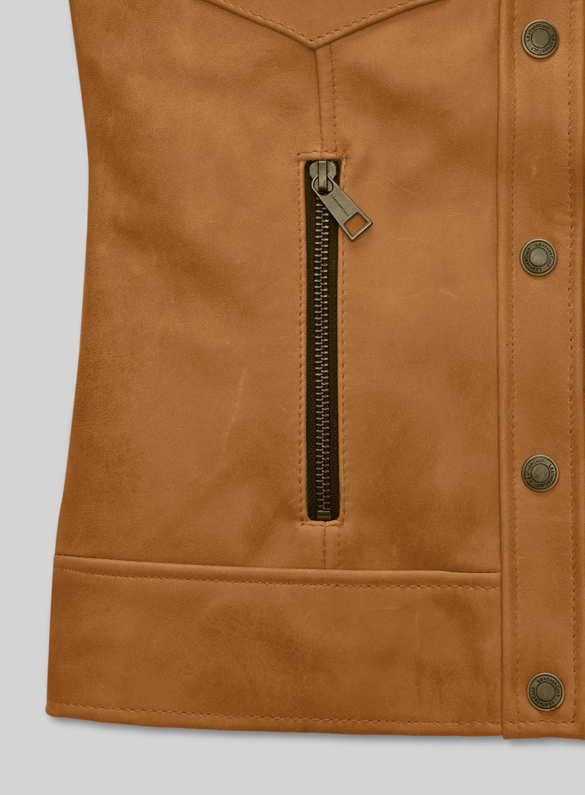 Close-up of tan leather jacket zip pocket and snap button placket
