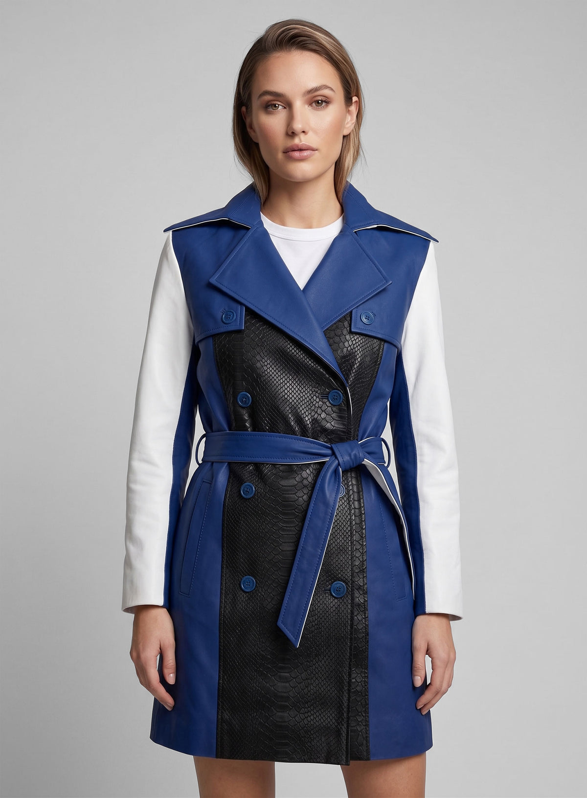 Woman wearing a double-breasted color contrast leather trench coat in blue, black and white with belt
