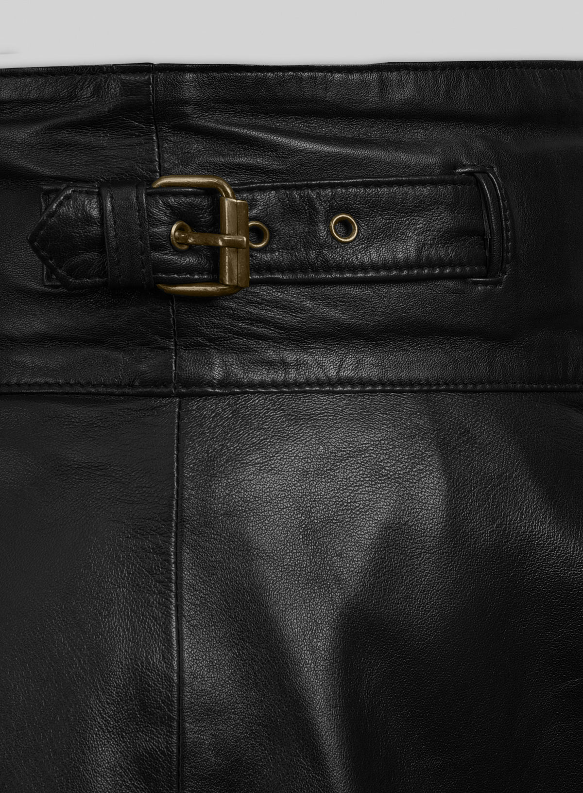 Close-up of brass buckle strap and eyelet on a black leather flare skirt waistband