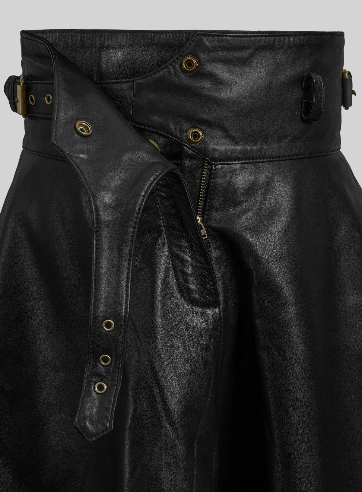 Detail of black leather flare skirt with open waistband, snaps, zipper and eyelet strap
