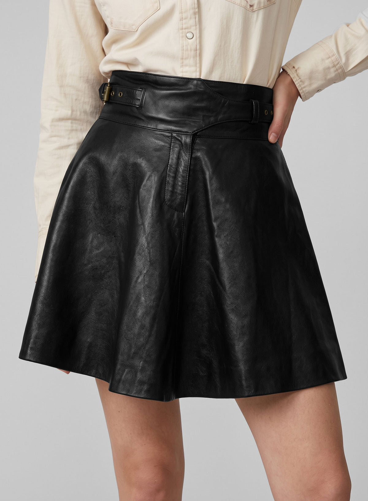 Woman wearing a black cowboy flare leather skirt with a cream western shirt, close-up