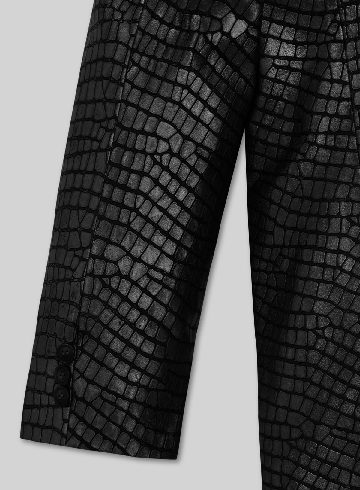 Close-up of black croc-embossed leather blazer sleeve with button cuff