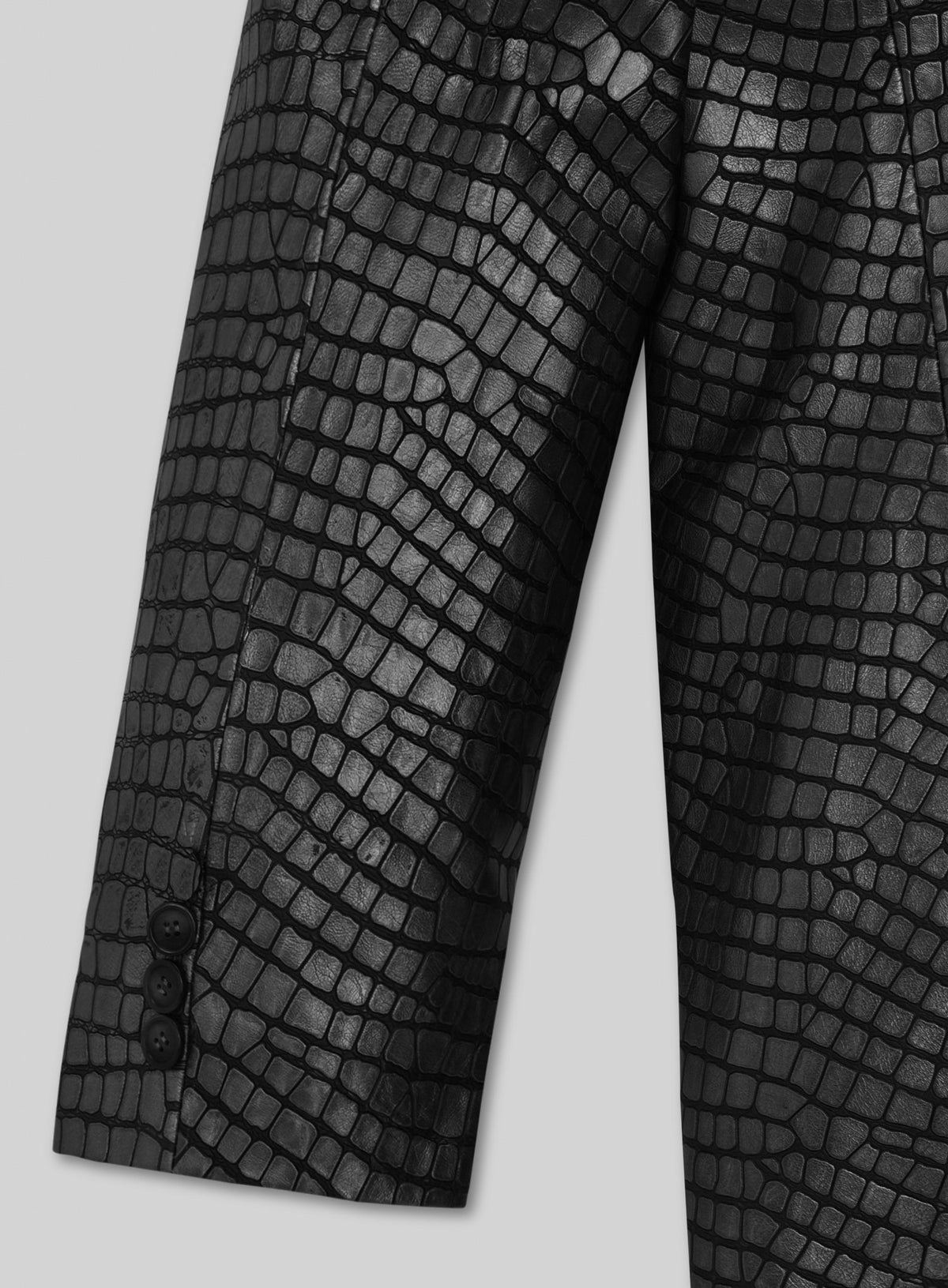 Close-up of sleeve with cuff buttons on a black croc-embossed leather blazer