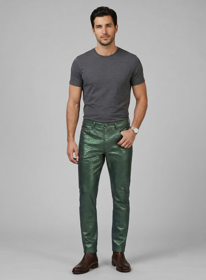 Full-length view of a man in metallic green croc-embossed leather pants, grey tee and brown boots