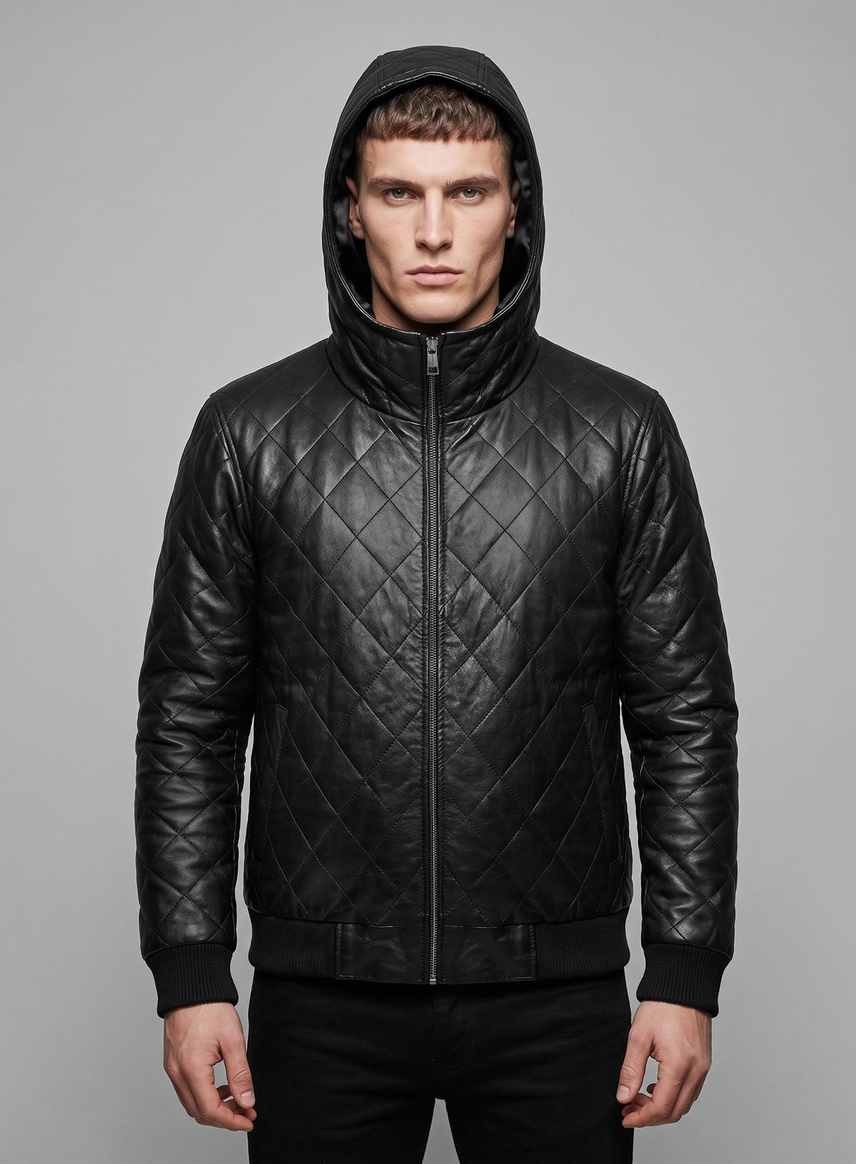 Man wearing a black quilted leather bomber jacket with hood up