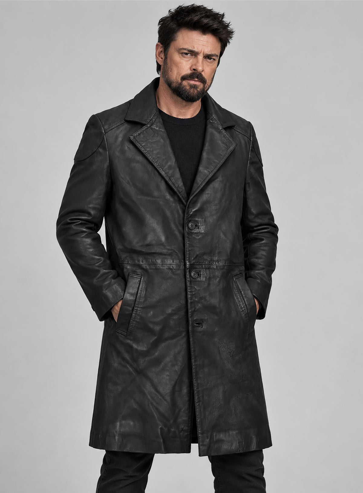 Man wearing a black leather long coat with notch lapel, hands in pockets