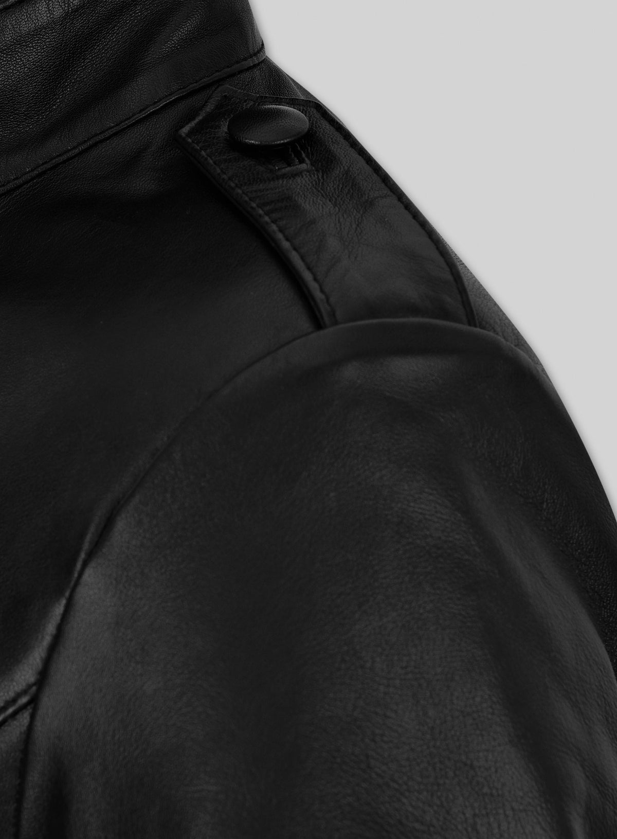 Close-up of shoulder epaulette and button on a black leather jacket