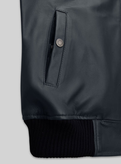 Close-up of a snap-button welt pocket and ribbed hem on a grey-blue leather bomber jacket