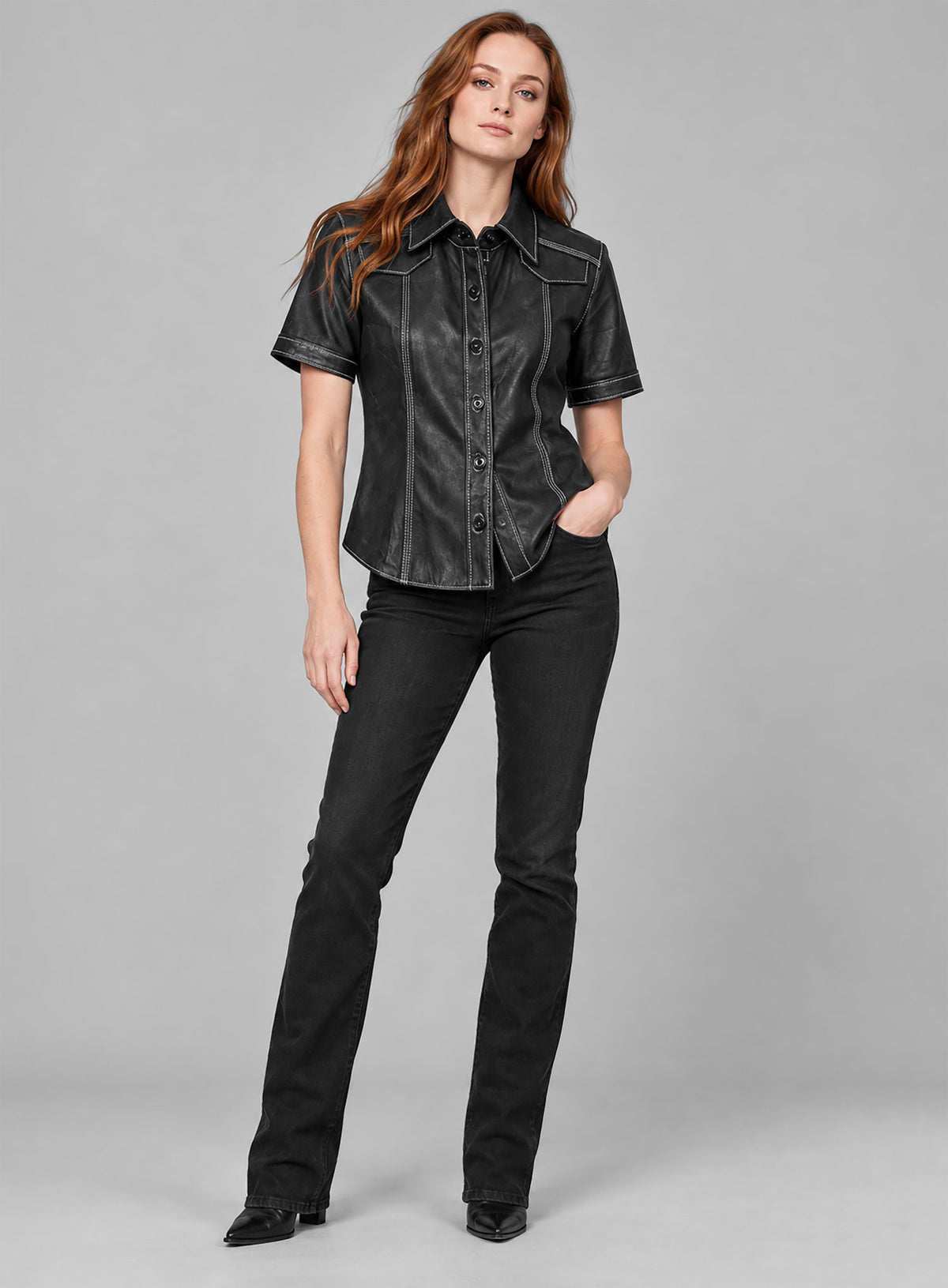 Full-length view of a woman in a black leather shirt, black jeans and heeled boots