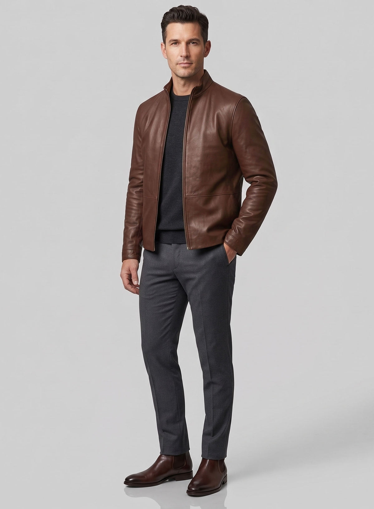 Full-length view of man in a brown leather jacket with grey trousers and Chelsea boots