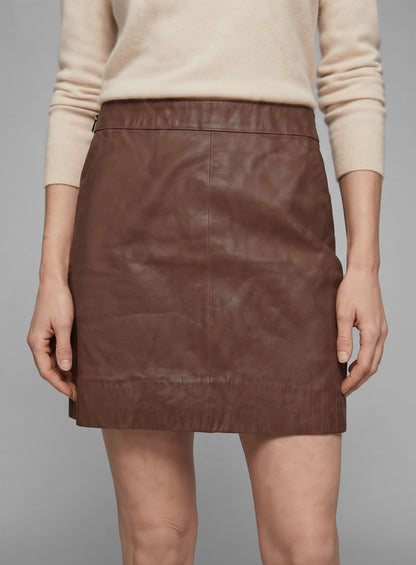Close-up of a tan brown washed wax leather mini skirt on a model, with side zipper