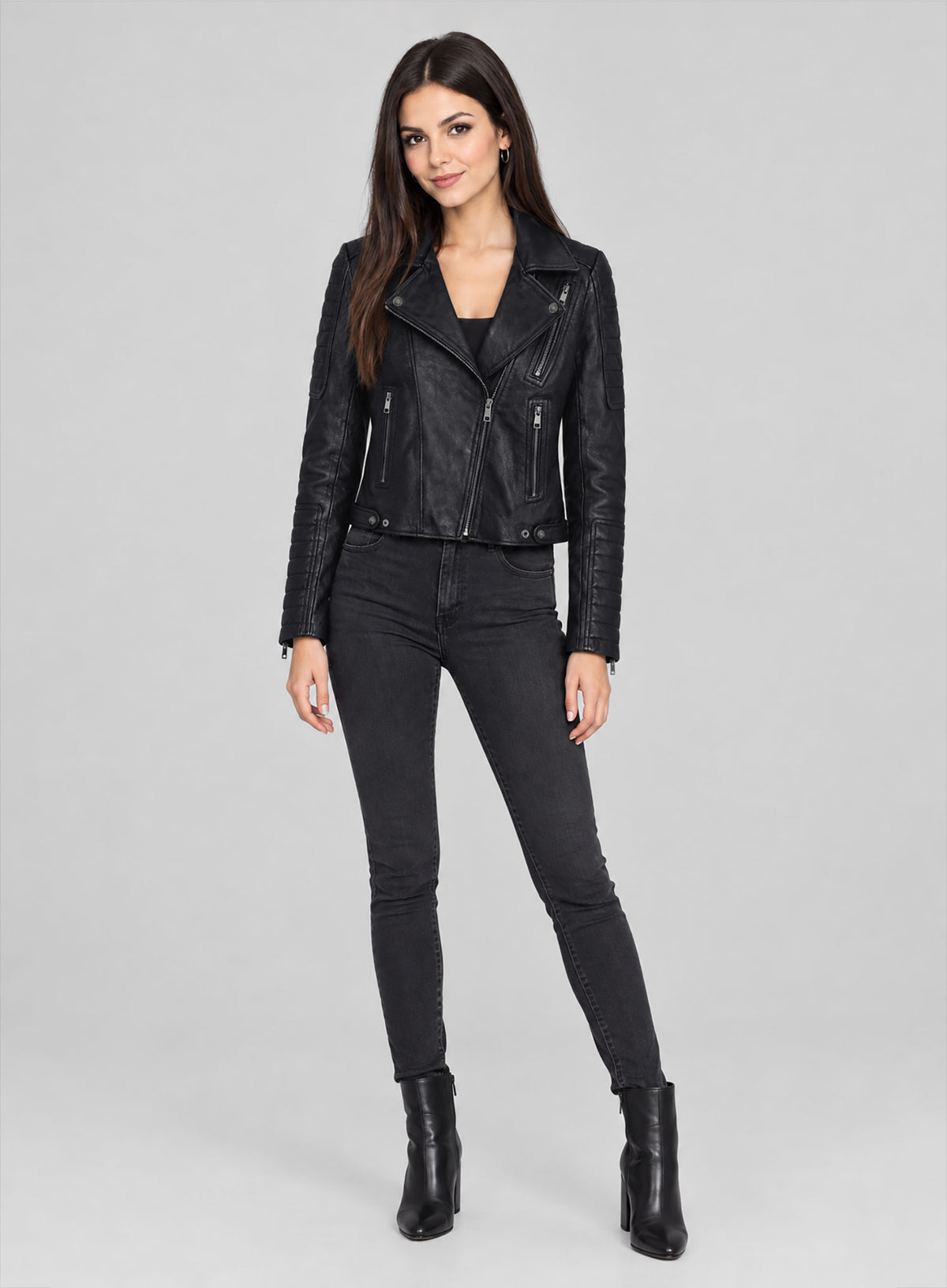 Full-length view of a woman wearing a black quilted-sleeve leather biker jacket with skinny jeans