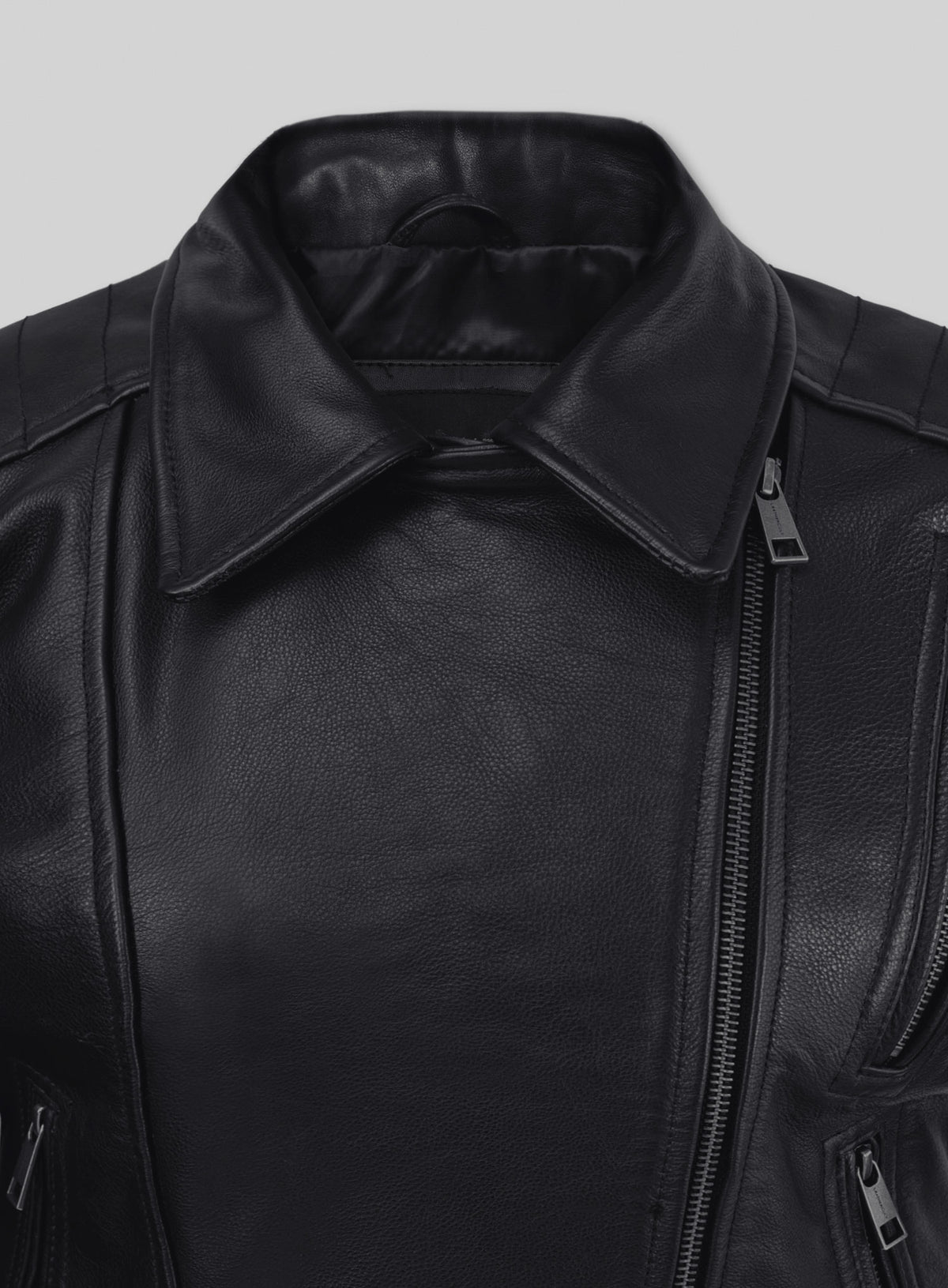 Close-up of the collar and asymmetric front zip of a black leather biker jacket
