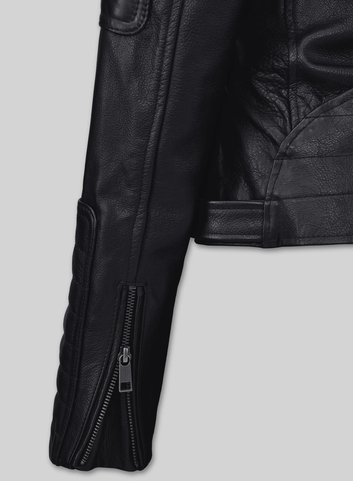 Close-up of a black leather biker jacket sleeve with a zip cuff and quilted panel