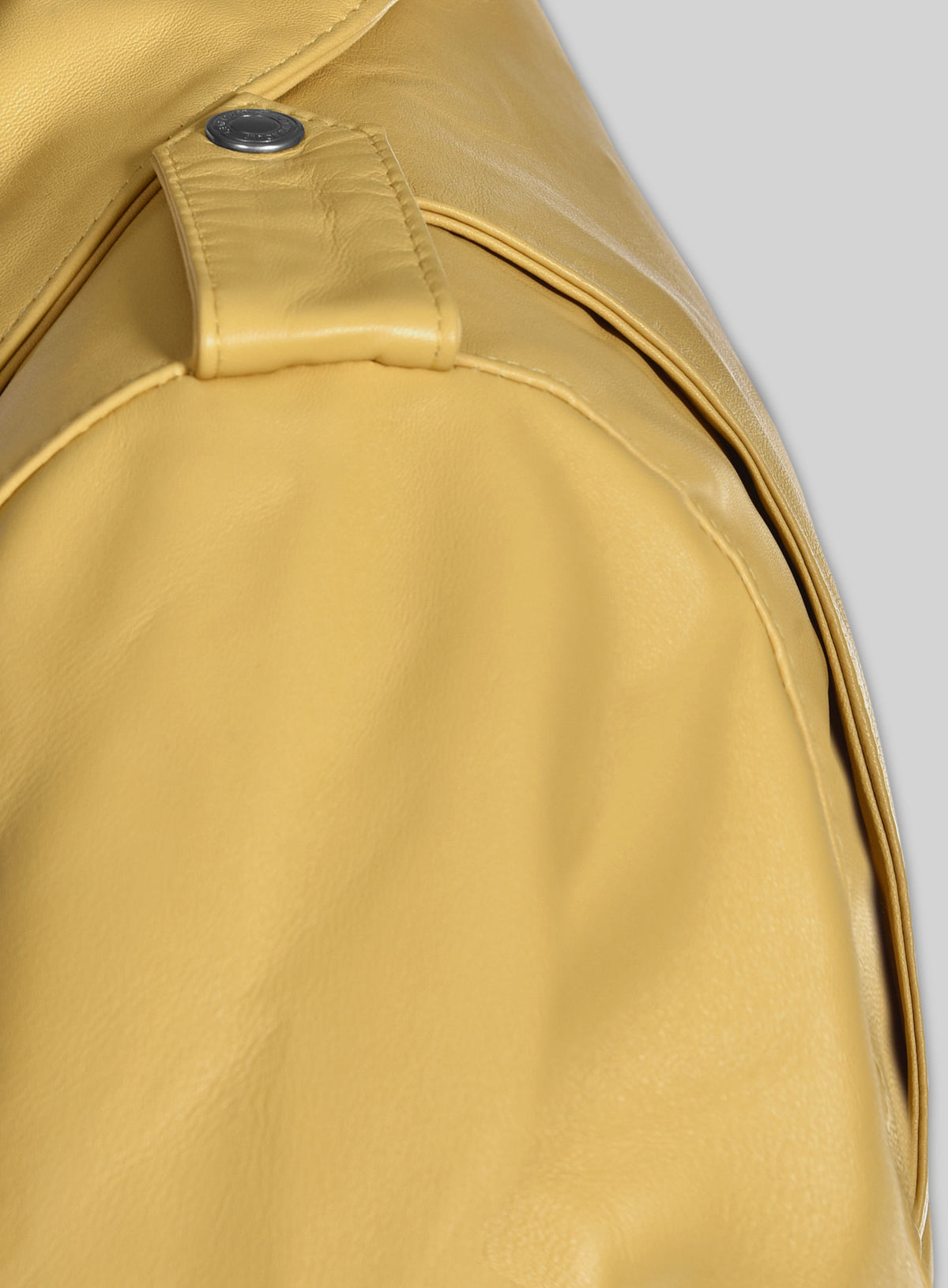 Close-up of shoulder epaulette and snap on a yellow leather jacket